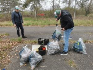 Efter nogle timers affaldsindsamling i Granskoven ved Halsskov Havn i Korsør, bliver affaldet først sorteret, lagt i plastsække og afslutningsvis vejet med bagagevægt. På billedet ses Stig og Jonas, der er i gang med at veje af. Begge er iført grøn-hvide kasketter med sort Green Heroes logo.